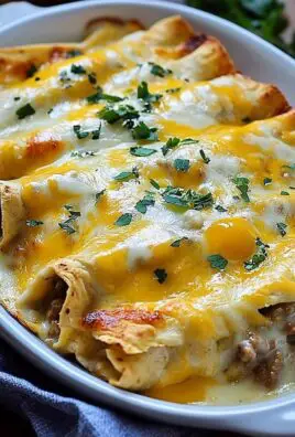 Close-up of cheesy baked beef enchiladas topped with melted cheddar and parsley in a white casserole dish